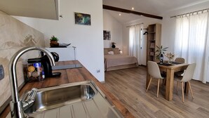 Un espace de vie compact comprenant une kitchenette, un coin repas et une chambre.