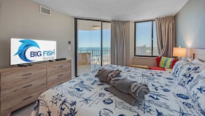 A hotel room with a bed, a TV, a balcony with a view, and a sign for Big Fish Rentals.