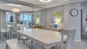 A dining area with a large table, benches, and a clock on the wall.