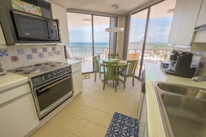 Enjoy ocean views from the kitchen and dining area, featuring a microwave, stove, oven, sink, and coffee machine.