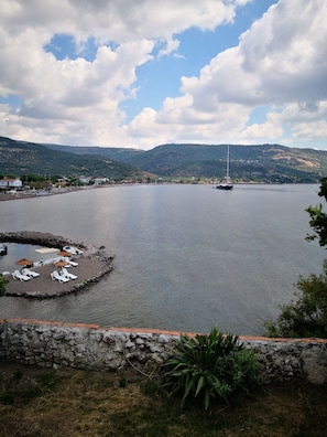 Un port de plaisance avec des bateaux, un petit quai doté de chaises longues et de parasols, et un mur de pierre au premier plan.