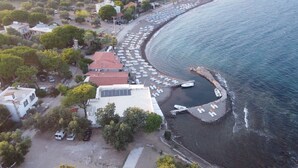 Vue aérienne d’une zone côtière avec un port de plaisance, des bateaux et une rangée de bâtiments situés en bord de mer.