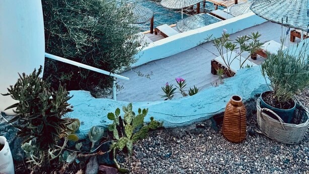Une terrasse en bord de mer avec une plateforme en bois, des parasols et des plantes en pot.