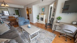 A modern living room with a grey sofa, a coffee table, and a TV mounted on the wall. - New Low Floor Direct Ocean Front at Sands Beach Club (Myrtle Beach)