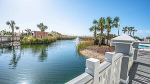 A calm waterway with a wooden walkway and palm trees.