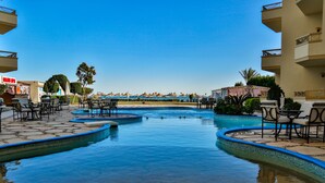 A pool area with multiple seating arrangements and a view of the beach.