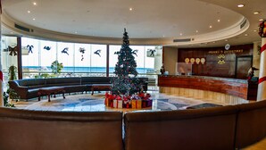 A lobby with a Christmas tree, seating area, and a reception desk.