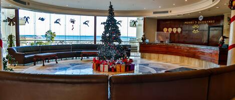 Un vestíbulo con un árbol de Navidad, zona de estar y un mostrador de recepción.