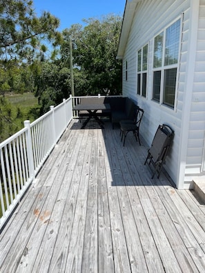 Une terrasse en bois avec une rambarde blanche, une table et deux chaises.
