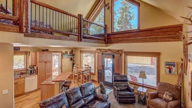 A spacious living area with a high ceiling, a dining area, and a kitchen.