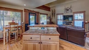 A spacious kitchen with wooden cabinets, a dining area with a wooden table and chairs, and a large window providing natural light.