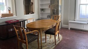 Een eetruimte met een houten tafel en stoelen, een inbouwboekenplank en hanglampen.