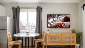 Eine moderne Küche mit einem runden Esstisch, zwei Holzstühlen, einem Holzschrank und einem Topf mit Pflanze.