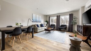 Un salon moderne comprenant un coin repas, un canapé, une table basse et un téléviseur.