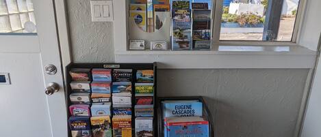 A room with a window overlooking a residential area, a door, and a display of travel books and maps.