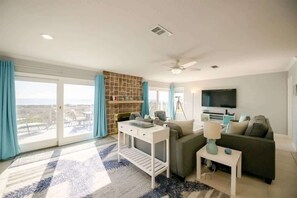 A modern living room with a sofa, a coffee table, a TV, and a fireplace. - Paradise by the C (Fernandina Beach)