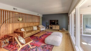 A modern living room with a wooden wall, a sofa, a coffee table, and a patterned rug.