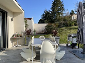 Relax outdoors with a patio table and chairs, surrounded by lush greenery and a beautifully manicured lawn.