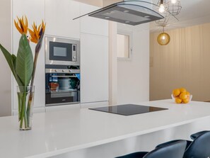 Et moderne køkken med indbygget ovn, mikrobølgeovn og en glasvase med blomster på bordet.