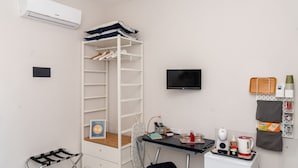 A compact room with a white wardrobe, a small desk with a computer, a TV, and a wall-mounted tray with a kettle and cups. - Casa Christal (Sant´Agnello)