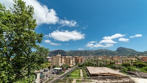 A view of a coastal town with buildings, a parking lot, and mountains in the background. - Casa Christal (Sant´Agnello)