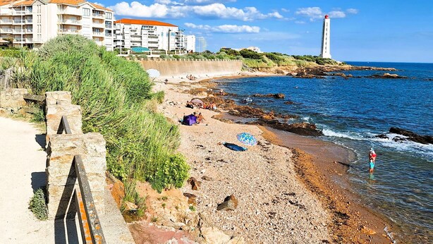Un paisaje costero con una playa, un litoral rocoso y un faro.