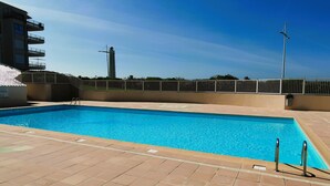 Una piscina rectangular con agua azul cristalina, rodeada por una solana con baldosas.
