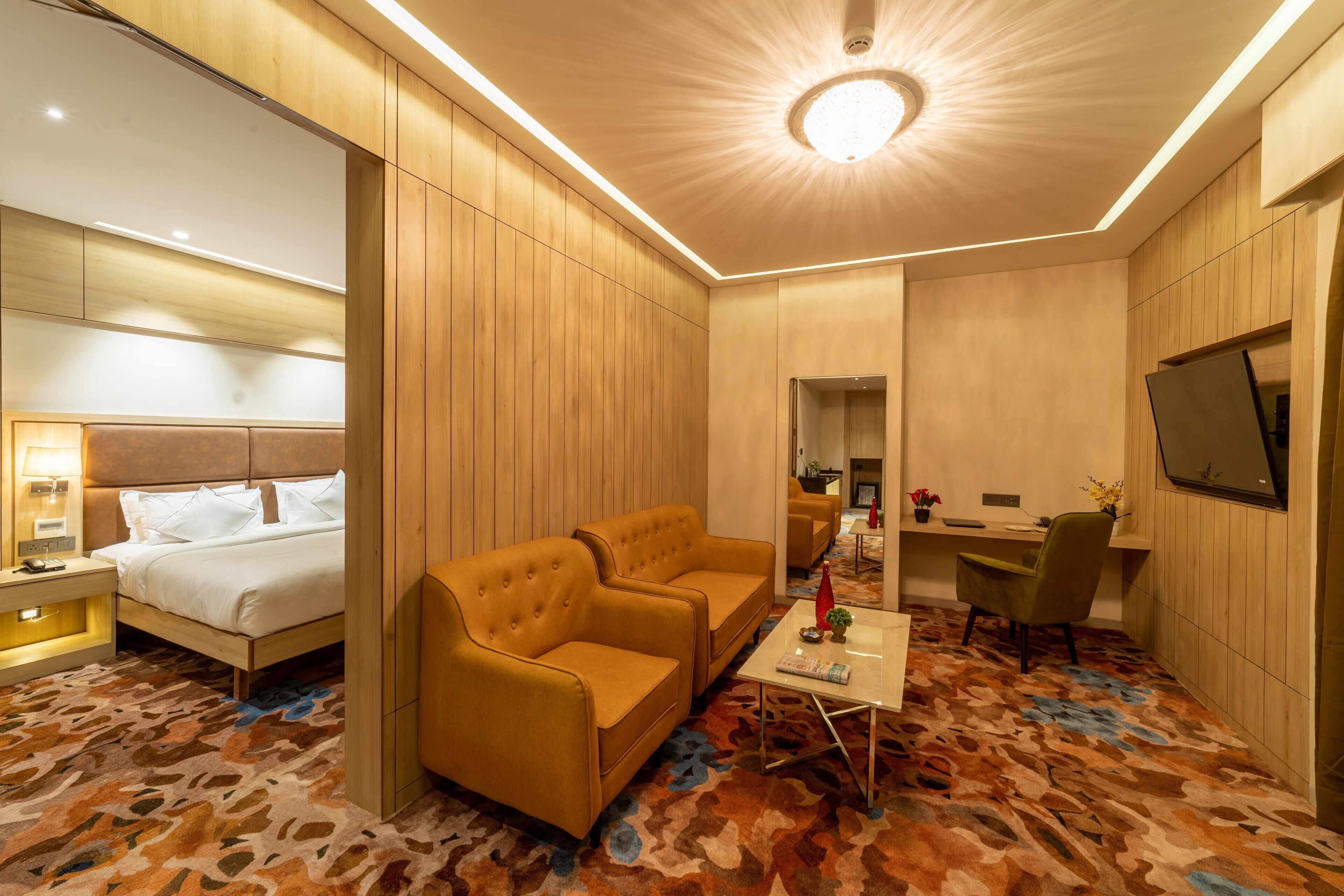 A hotel room with a bed, two sofas, a desk, and a TV.