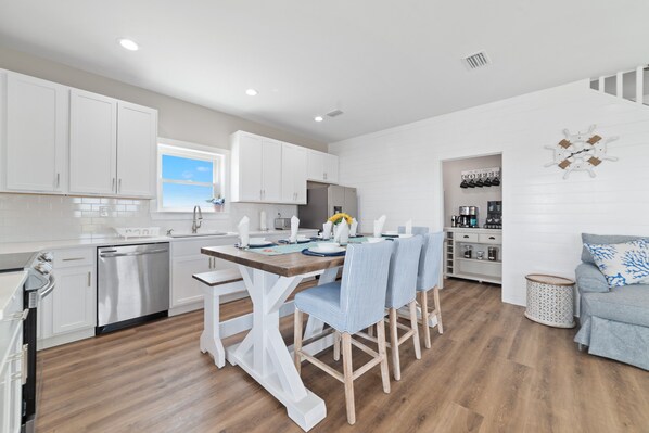 A modern kitchen with white cabinets, a wooden dining table, and striped chairs.
