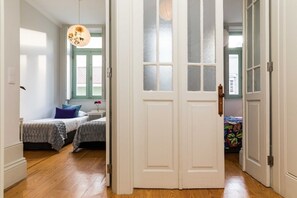 A room with two beds, a window with frosted glass, and a hanging light fixture.
