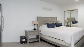 Een slaapkamer met een bed, nachtkastjes, een spiegel en een bord aan de muur.