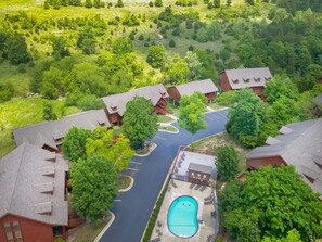 Vista aérea de um resort com várias cabanas, uma piscina e vegetação ao redor.