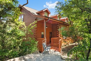 A log cabin with a porch, a bench, and a small garden area.