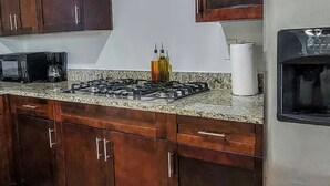 A kitchen with granite countertops, a gas stove, a coffee maker, and a water dispenser. - Amazing Melly's (Tampa)