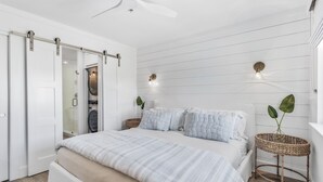Een slaapkamer met een bed, een schuifdeur, een plafondventilator en een wandlamp.