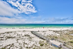 A beach with a wooden boardwalk leading to a building with a flat roof. - Beautifully Renovated Ocean Front Condo in High Demand Area! (Santa Rosa Beach)