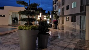 A courtyard with potted plants, a pool, and a building with multiple floors and balconies.