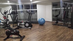 A modern gym with cardio machines, a large exercise ball, and weightlifting equipment.
