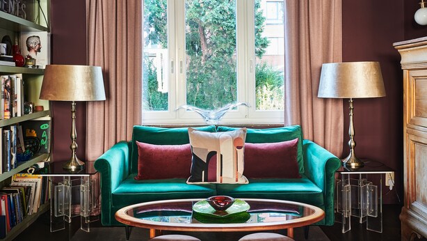 A room with a green sofa, two lamps, a coffee table, and a bookshelf. - Charming 2-bedroom Home & Garden (Brussels)