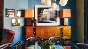 A dining area with a glass table, chairs, a wooden cabinet, and framed pictures on the wall. - Charming 2-bedroom Home & Garden (Brussels)