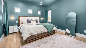 A bedroom with teal walls, a wooden bed frame, a white bedspread, and a patterned rug. - Mountain Home near Lakes w/Hot Tub & Putting Green (Heber City)