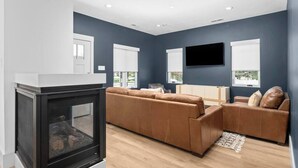 A modern living room with a sectional sofa, a fireplace, and a flat-screen TV mounted on the wall. - Mountain Home near Lakes w/Hot Tub & Putting Green (Heber City)