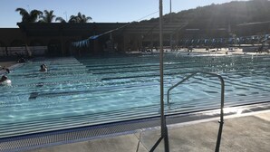 A swimming pool with multiple lanes, a lifeguard stand, and a covered spectator area. - Colorful Warm Weather Jewel House 10,000 sq ft lot. (Menifee)