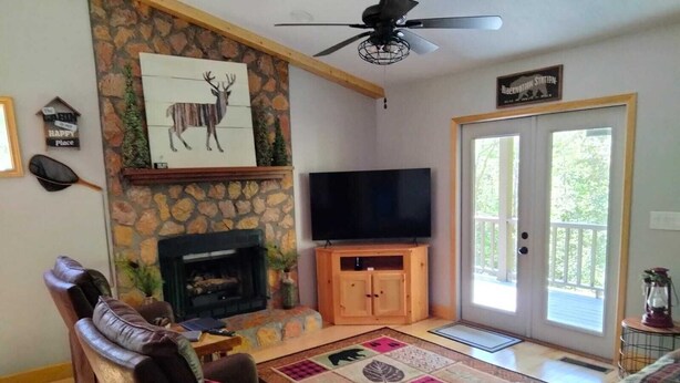 A cozy living room with a stone fireplace, a flat-screen TV, and comfortable seating. - Beary’s Den where Chic meets Country in this Cozy Cabin (Murphy)