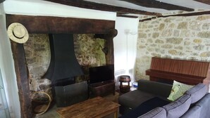 A cozy living room with a stone fireplace, a television, a sofa, and a wooden coffee table. - Quercy house at the foot of the cliffs (Vayrac)