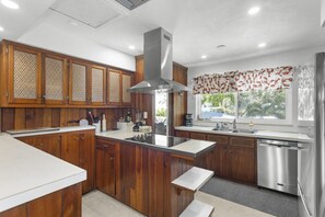 Une cuisine dotée de meubles en bois, d’un îlot central, d’appareils électroménagers en acier inoxydable et d’une fenêtre donnant sur un paysage verdoyant.