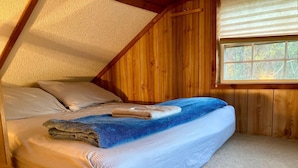 Een gezellig slaapkamer met een schuine kap, houten wanden en een raam.