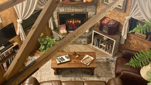 Un salon chaleureux avec une cheminée en pierre, un canapé en cuir et une table basse en bois.