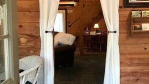 L'intérieur d'une cabane en bois, avec un lit, une table et une chaise.