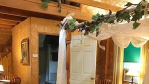 Un lit traditionnel à baldaquin, une commode en bois et un coin repas avec des chaises et une table.